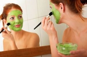 женщина наносит маску из глины зеленого цвета на лицо